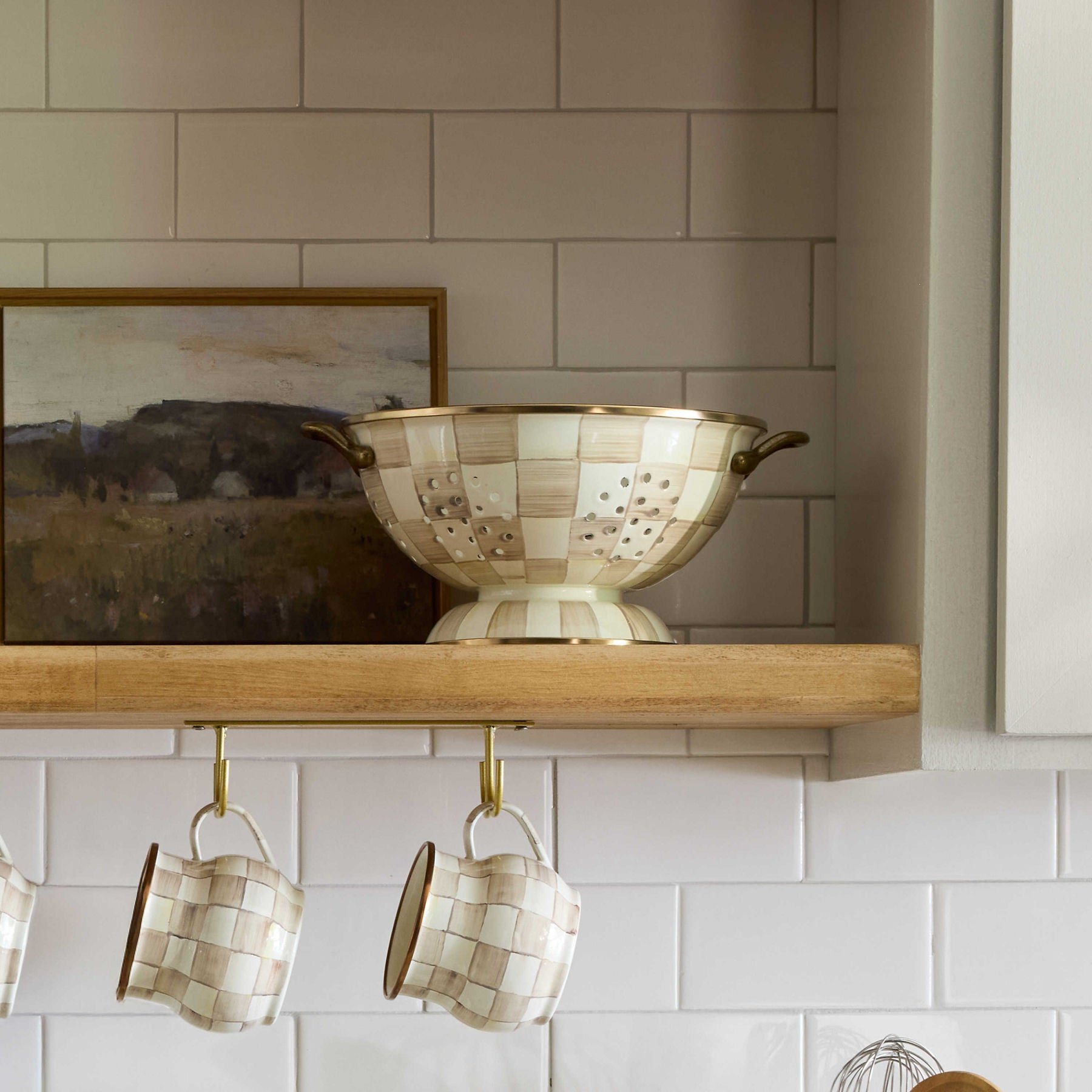 Velký cedník Mocha Check od MacKenzie-Childs, ručně malovaný kostkovaný vzor v kávových odstínech, robustní ocel, ucha s povrchem starožitné mosazi, Waterfall Bathrooms.

